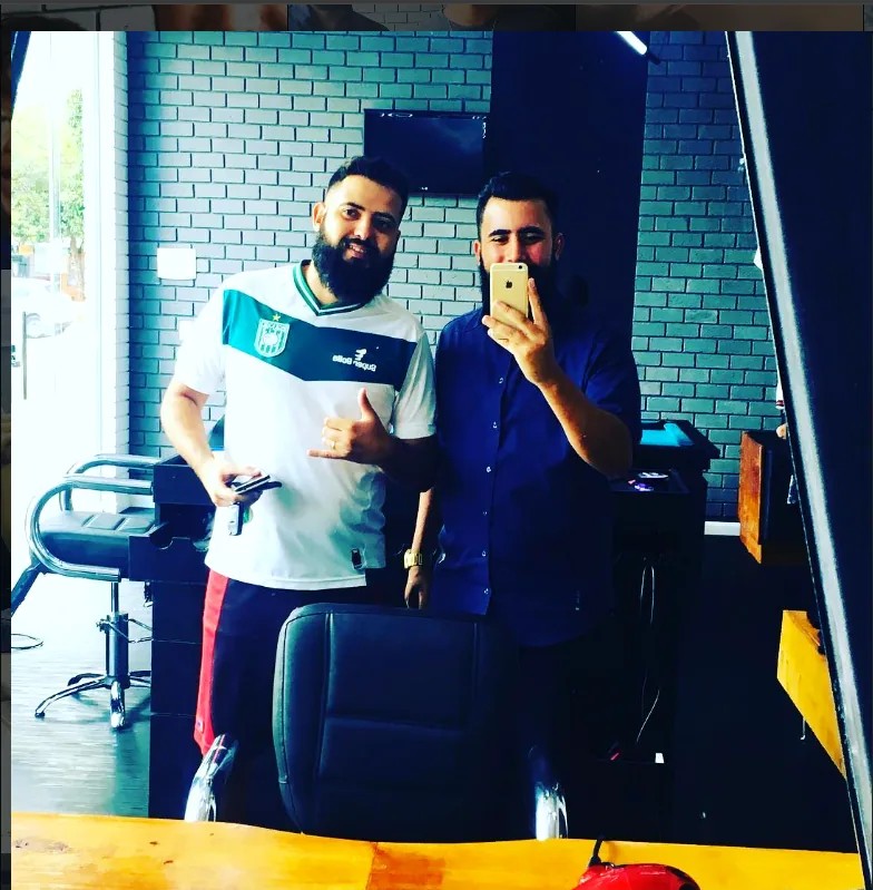 Thomas Gabriel com cliente no espelho da barbearia